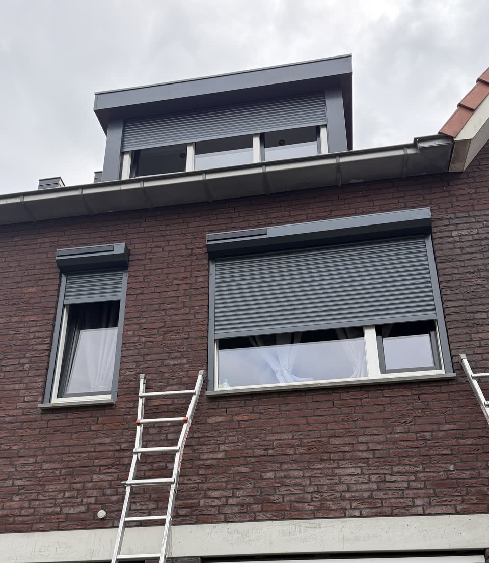 Voorgevel met rolluiken half neergelaten en een ladder tegen de gevel