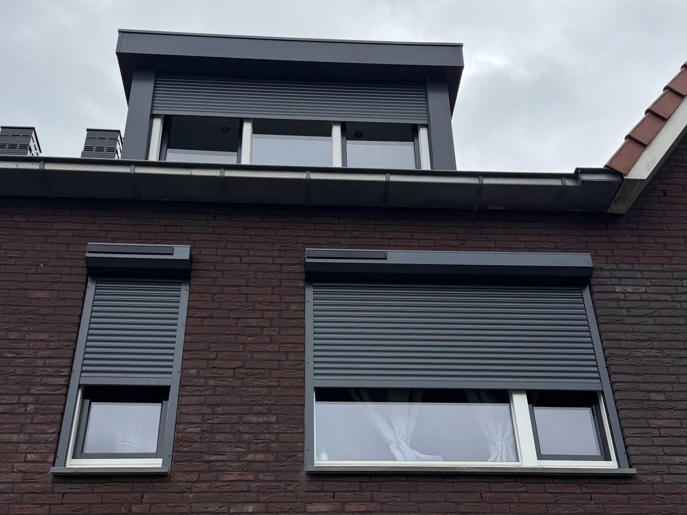 Eigen werk van RolluikBroers: antraciet solar rolluiken aan een rijwoning