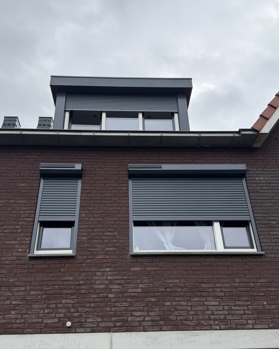 Voorgevel van een rijwoning met nieuwe antraciet rolluiken, driekwart neer