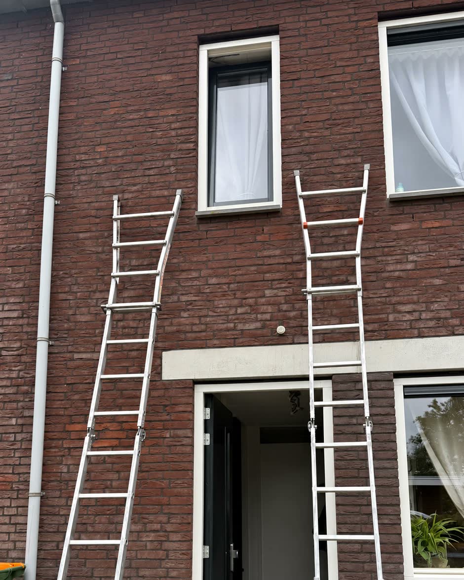 Twee ladders staan klaar tegen een voorgevel zonder rolluiken