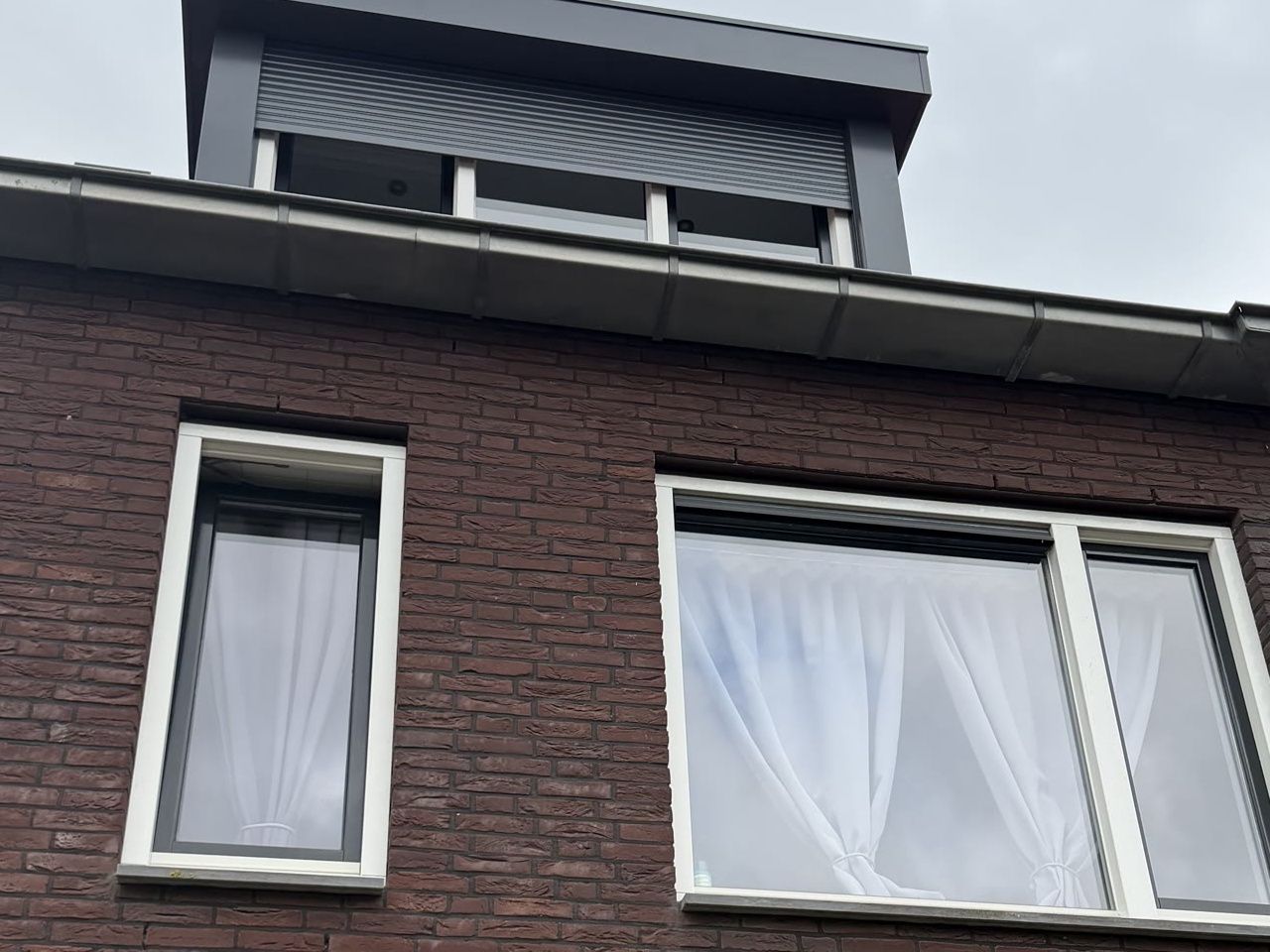 Voorgevel van een rijwoning zonder rolluiken op de eerste verdieping